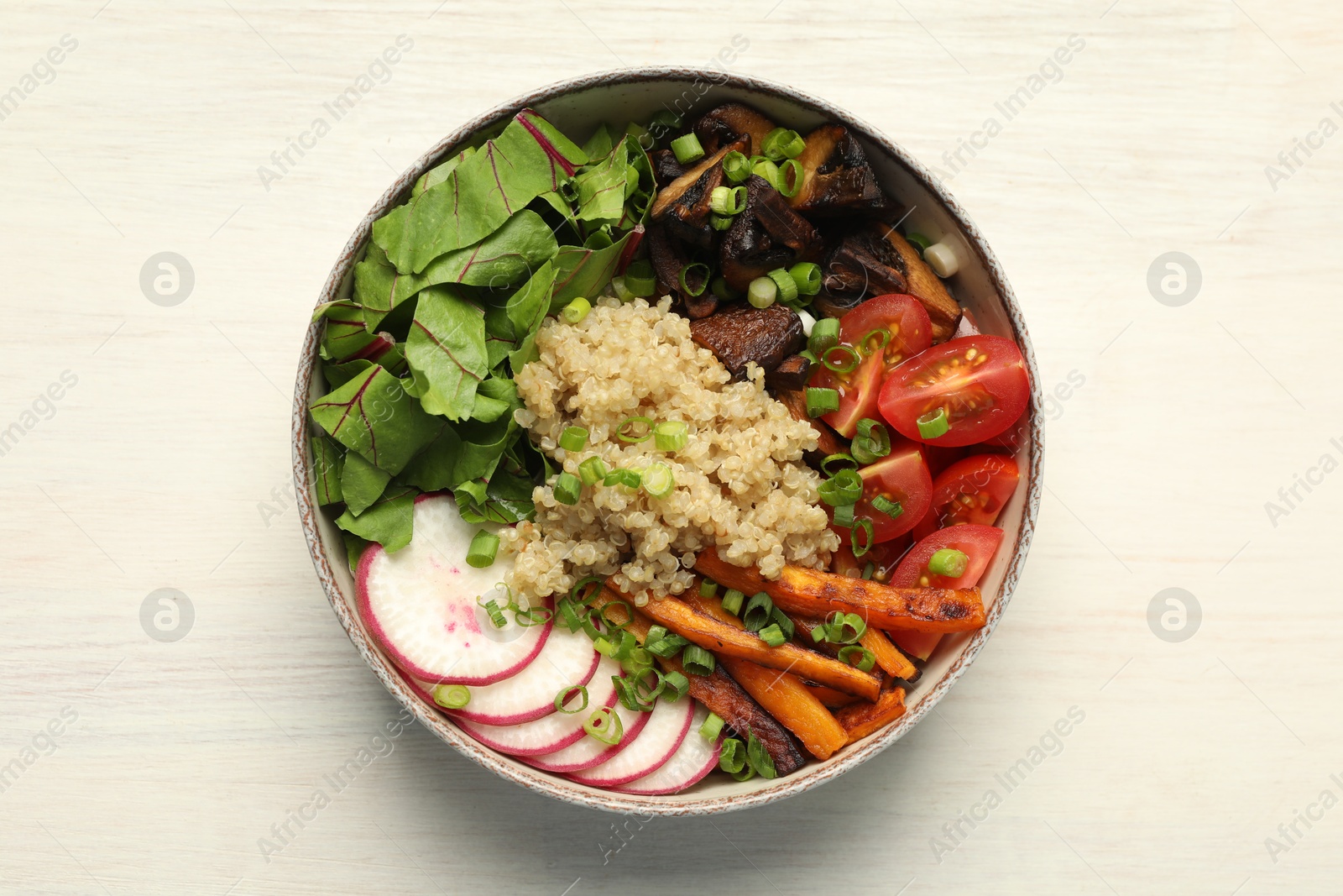 Photo of Healthy vegetarian food. Delicious Buddha bowl with quinoa, mushrooms and vegetables on light wooden table, top view