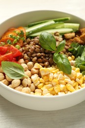 Photo of Healthy vegetarian food. Delicious Buddha bowl with lentils, tofu, chickpeas and vegetables on light wooden table, closeup