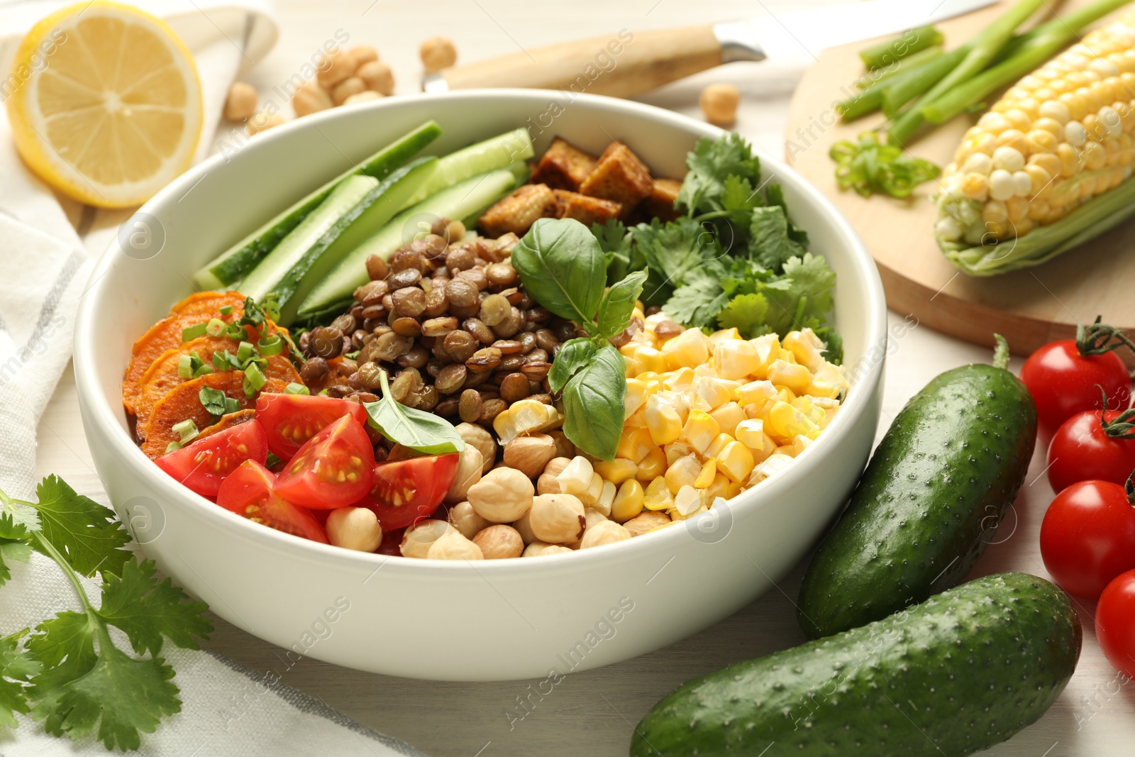 Photo of Healthy vegetarian food. Delicious Buddha bowl and ingredients on light wooden table, closeup
