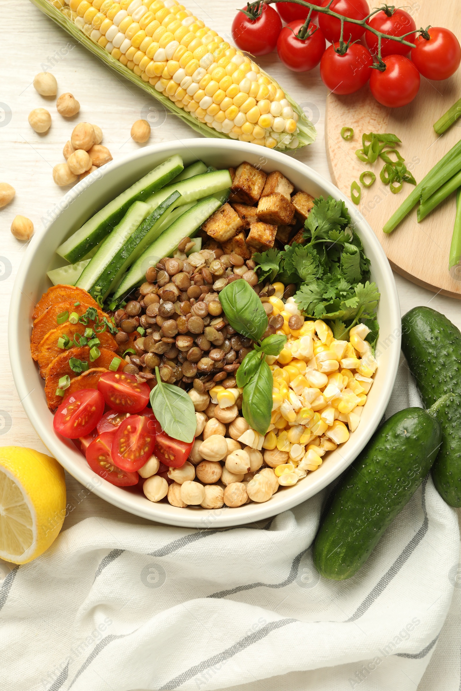 Photo of Healthy vegetarian food. Delicious Buddha bowl and ingredients on light wooden table, flat lay