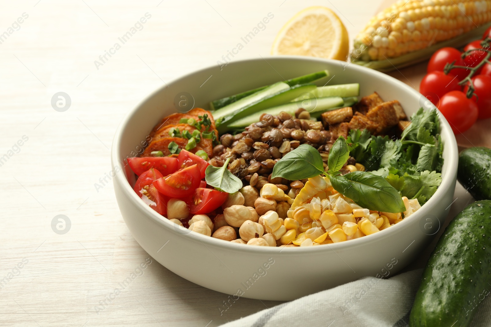 Photo of Healthy vegetarian food. Delicious Buddha bowl and ingredients on light wooden table, closeup. Space for text