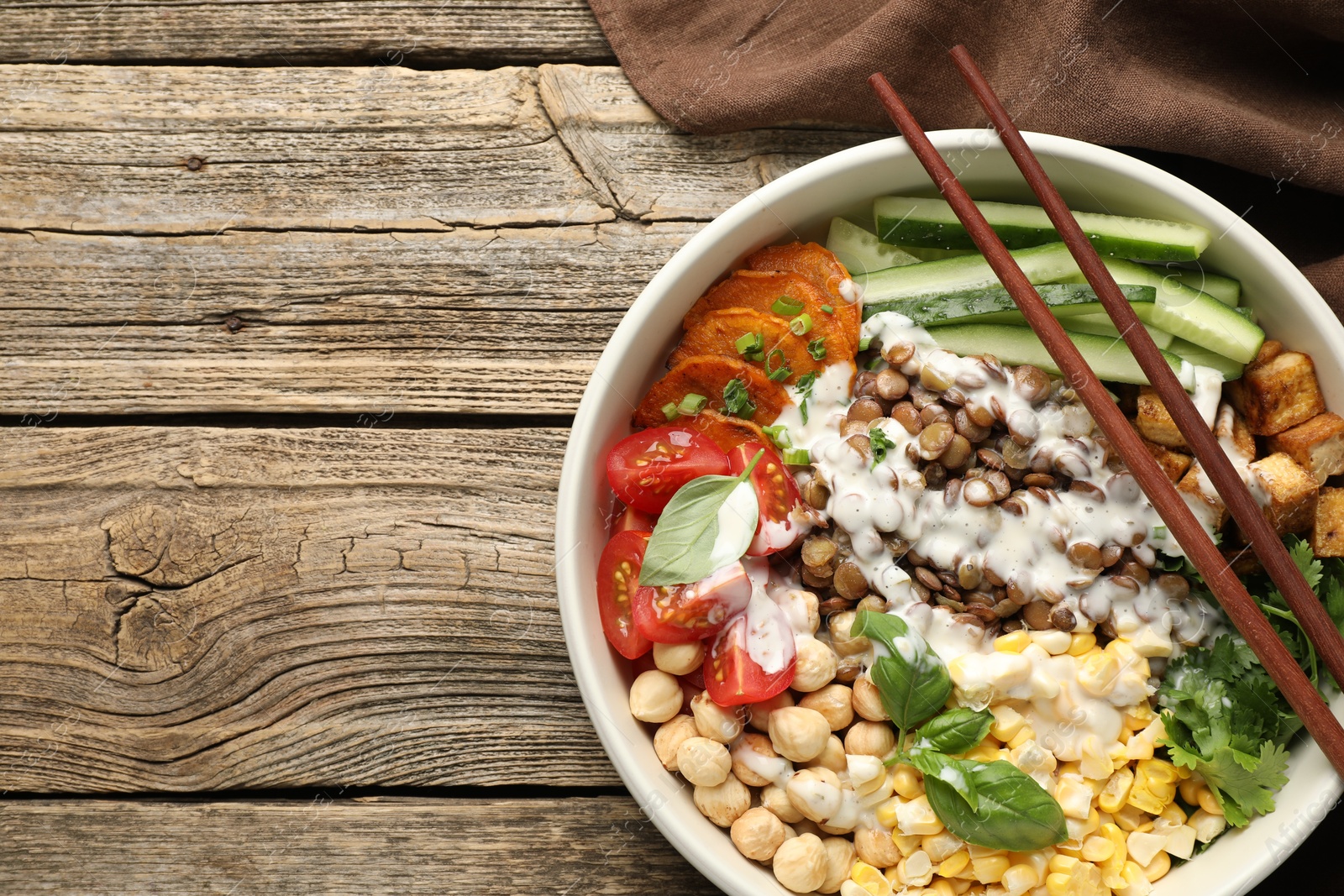 Photo of Healthy vegetarian food. Delicious Buddha bowl served on wooden table, top view. Space for text