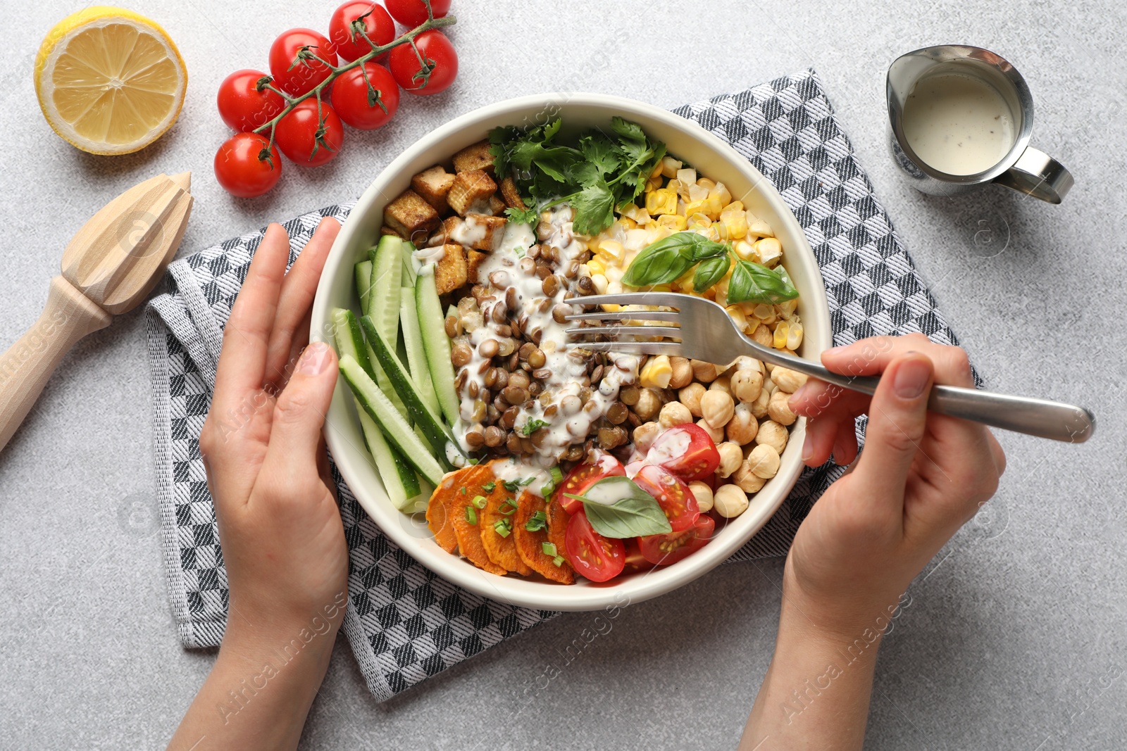 Healthy vegetarian food. Woman eating delicious Buddha bowl at light grey table, top view Photo of Healthy vegetarian food. Woman eating delicious Buddha bowl at light grey table, top view