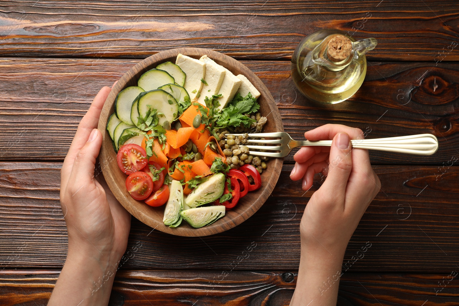 Healthy vegetarian food. Woman eating delicious Buddha bowl at wooden table, top view Photo of Healthy vegetarian food. Woman eating delicious Buddha bowl at wooden table, top view