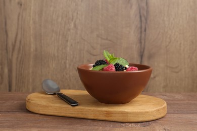Photo of Tasty yogurt with granola and berries in bowl on wooden table