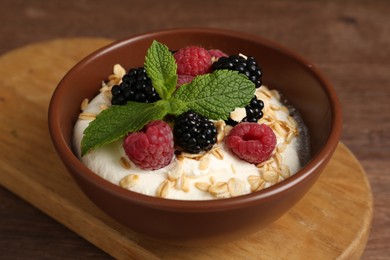 Photo of Tasty yogurt with granola and berries in bowl on wooden table, closeup