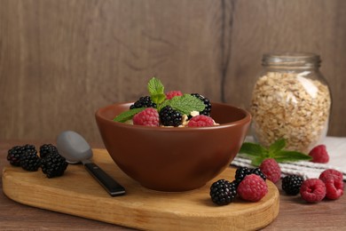 Photo of Tasty yogurt with granola and berries in bowl on wooden table, closeup