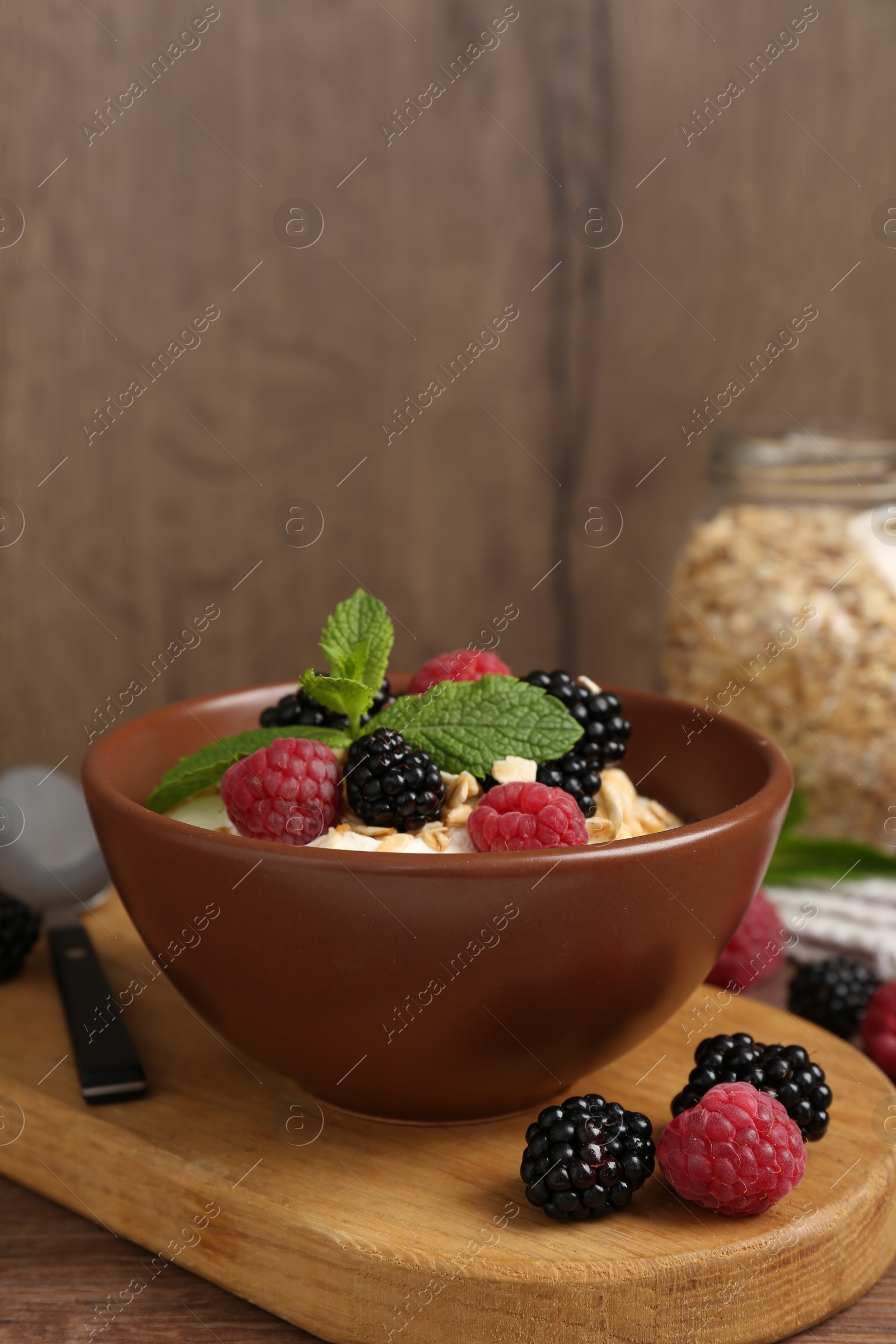 Tasty yogurt with granola and berries in bowl on wooden table, closeup. Space for text Photo of Tasty yogurt with granola and berries in bowl on wooden table, closeup. Space for text