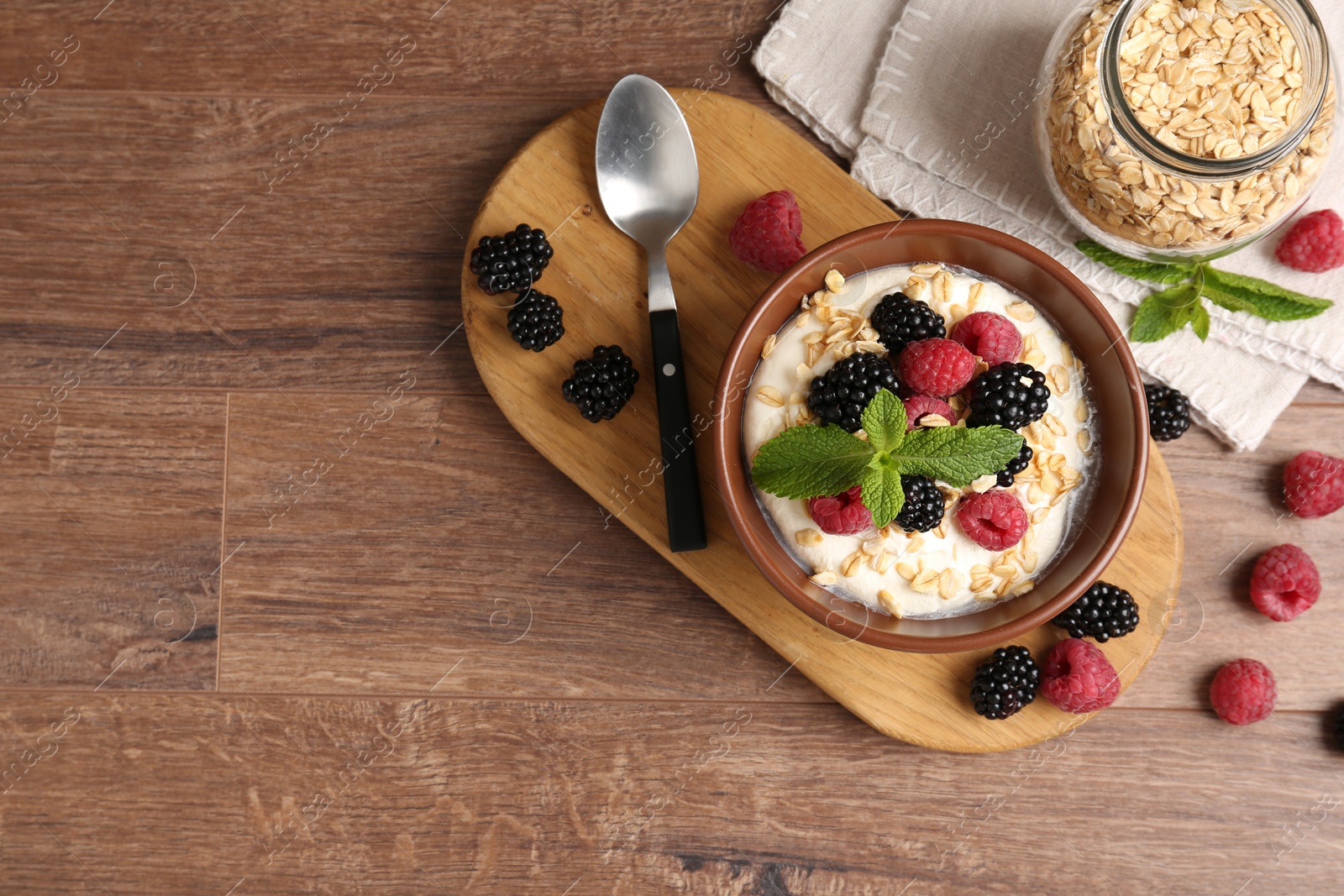 Tasty yogurt with granola and berries in bowl on wooden table, flat lay. Space for text Photo of Tasty yogurt with granola and berries in bowl on wooden table, flat lay. Space for text