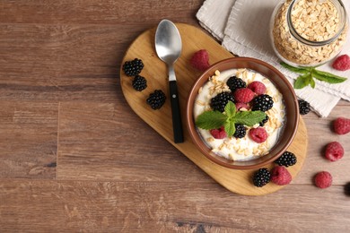 Photo of Tasty yogurt with granola and berries in bowl on wooden table, flat lay. Space for text