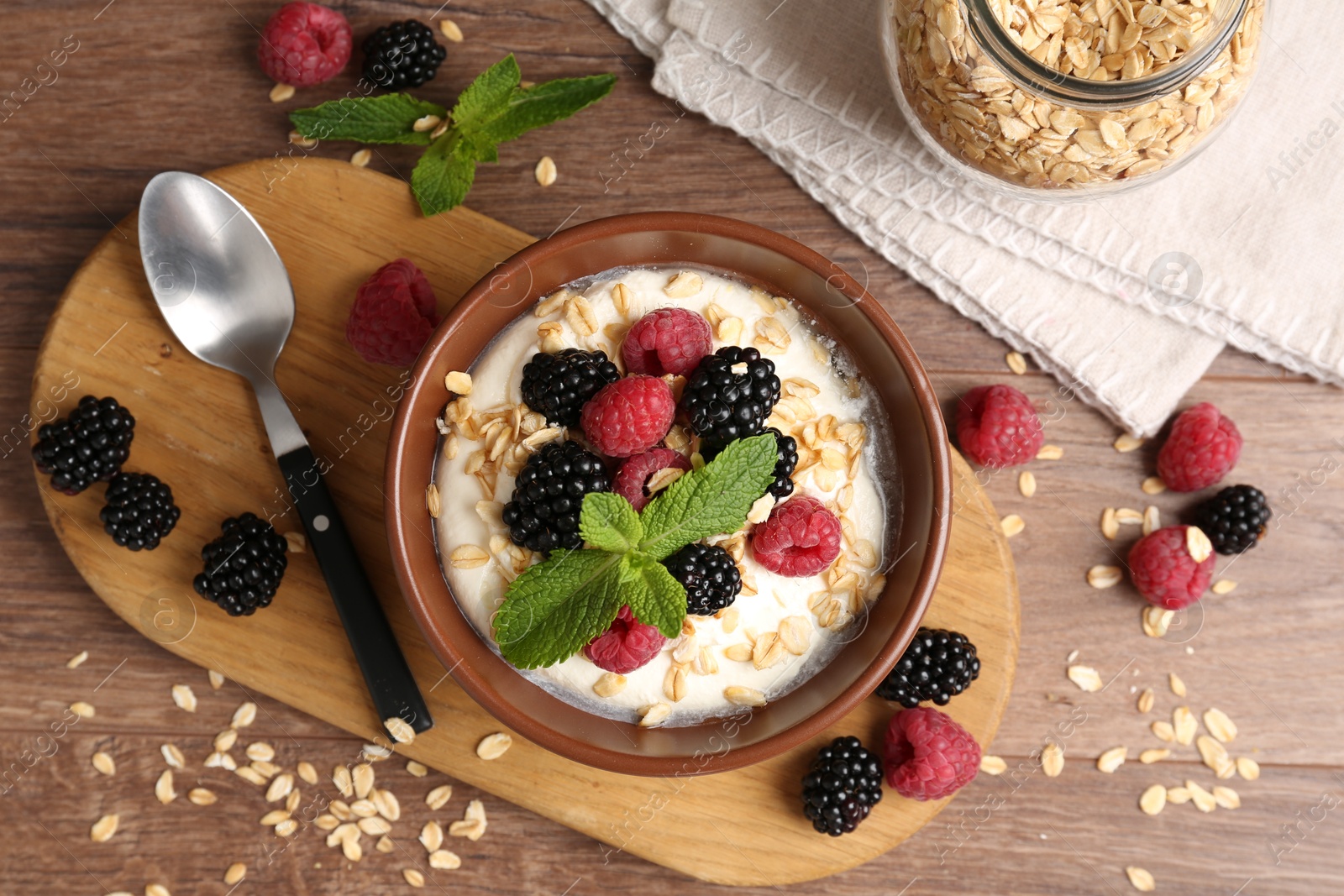 Tasty yogurt with granola and berries in bowl on wooden table, flat lay Photo of Tasty yogurt with granola and berries in bowl on wooden table, flat lay