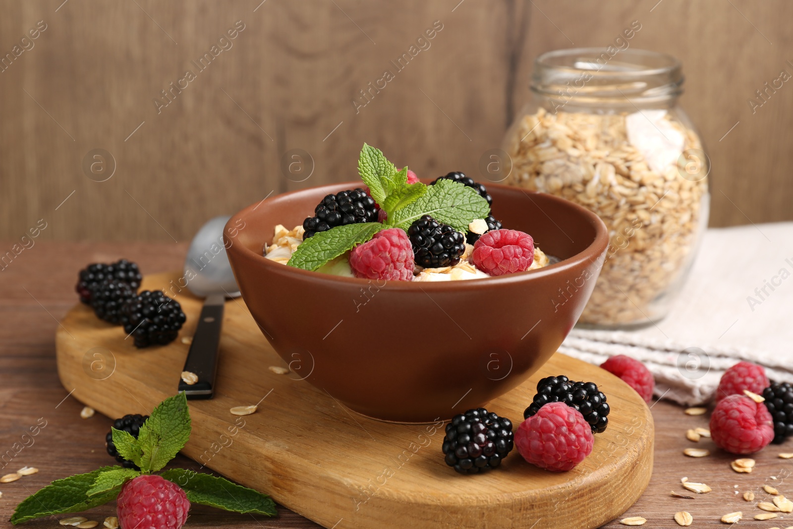 Tasty yogurt with granola and berries in bowl on wooden table, closeup Photo of Tasty yogurt with granola and berries in bowl on wooden table, closeup