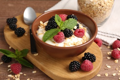Photo of Tasty yogurt with granola and berries in bowl on wooden table, closeup