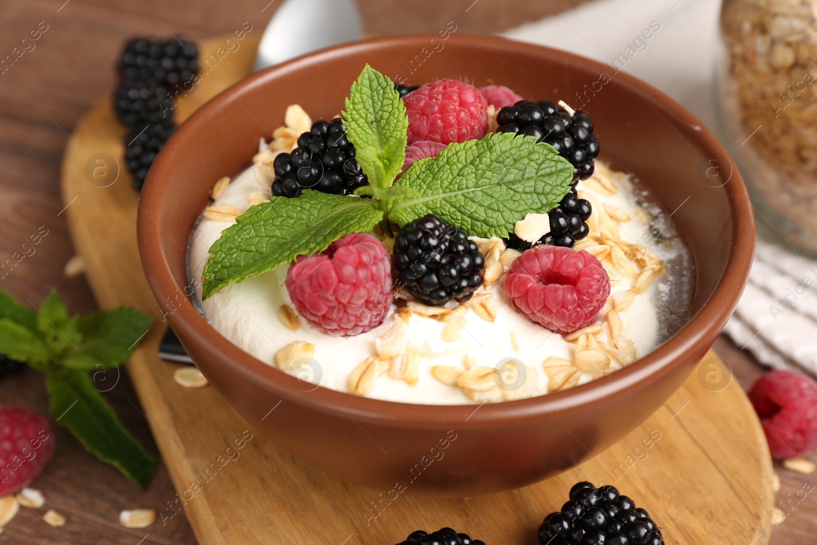 Tasty yogurt with granola and berries in bowl on wooden table, closeup Photo of Tasty yogurt with granola and berries in bowl on wooden table, closeup