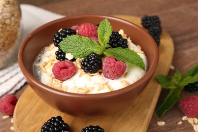 Photo of Tasty yogurt with granola and berries in bowl on wooden table, closeup