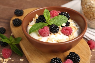 Photo of Tasty yogurt with granola and berries in bowl on wooden table, closeup