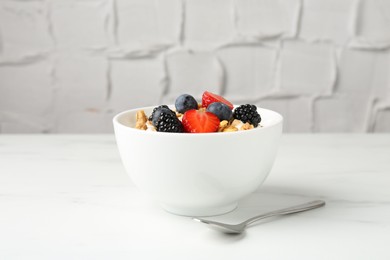 Photo of Tasty yogurt with granola and berries in bowl on white marble table, closeup