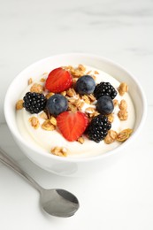 Photo of Tasty yogurt with granola and berries in bowl on white marble table, closeup
