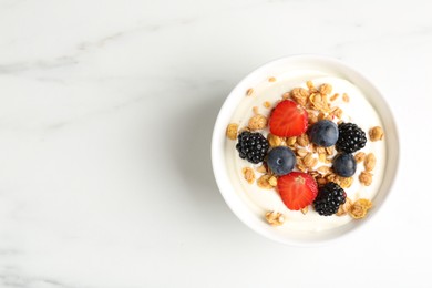 Photo of Tasty yogurt with granola and berries in bowl on white marble table, top view. Space for text