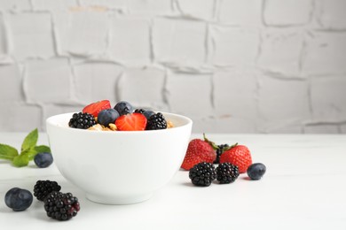 Photo of Tasty yogurt with granola and berries in bowl on white table, closeup. Space for text
