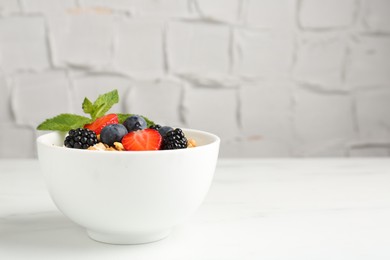 Photo of Tasty yogurt with granola and berries in bowl on white marble table, closeup. Space for text