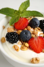 Photo of Tasty yogurt with granola and berries in bowl on white table, closeup
