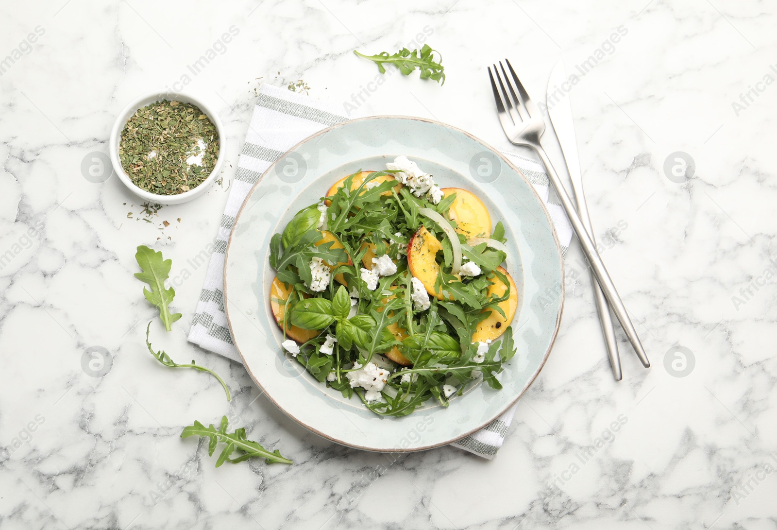 Tasty salad with arugula, cheese, peach, basil and spices on white marble table, flat lay Photo of Tasty salad with arugula, cheese, peach, basil and spices on white marble table, flat lay