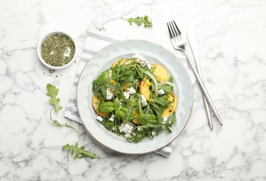 Photo of Tasty salad with arugula, cheese, peach, basil and spices on white marble table, flat lay