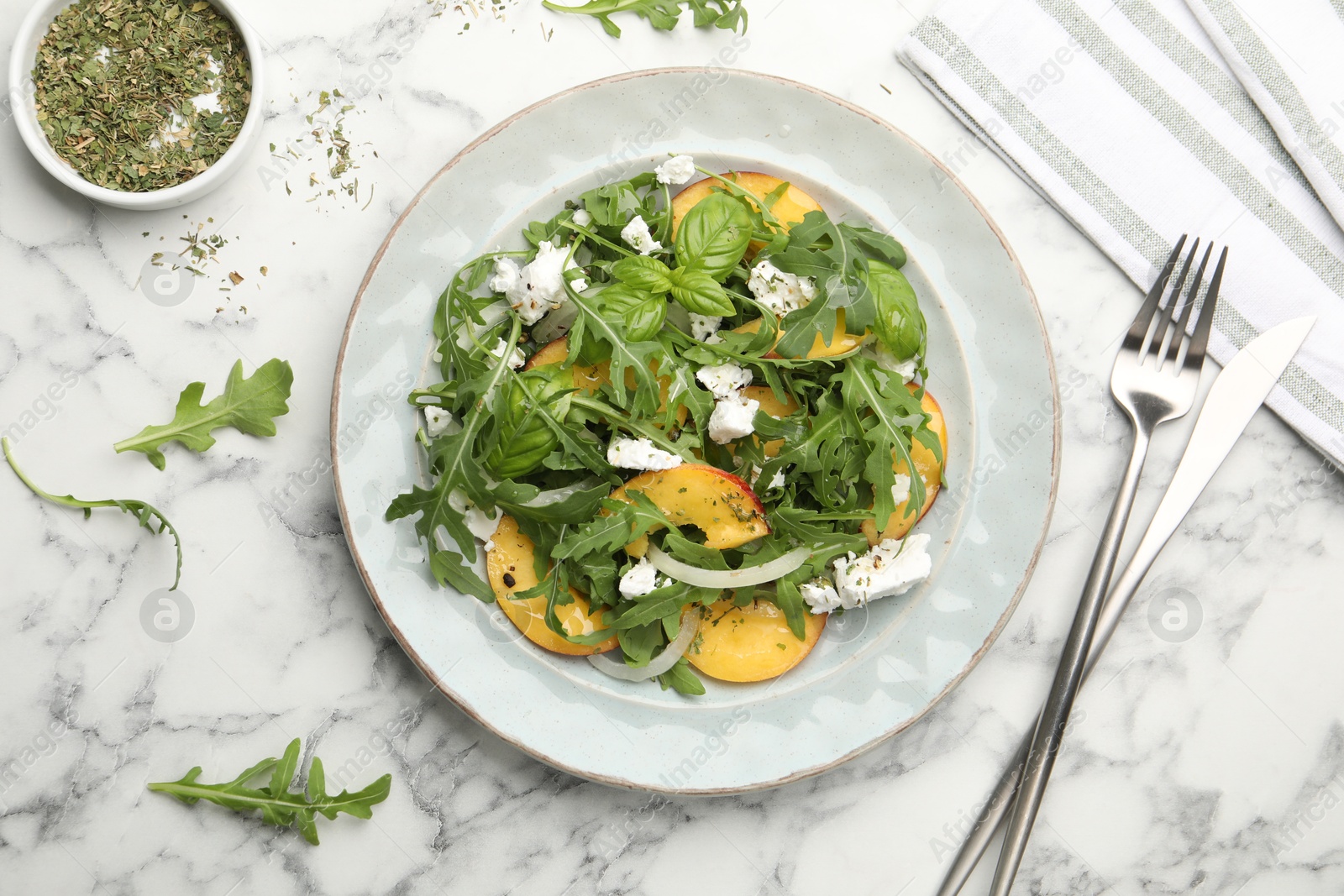 Tasty salad with arugula, cheese, peach, basil and spices on white marble table, flat lay Photo of Tasty salad with arugula, cheese, peach, basil and spices on white marble table, flat lay