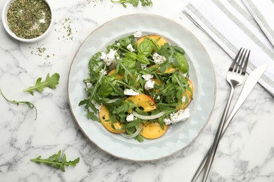 Photo of Tasty salad with arugula, cheese, peach, basil and spices on white marble table, flat lay