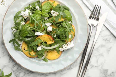Photo of Tasty salad with arugula, cheese, peach and basil on white marble table, flat lay