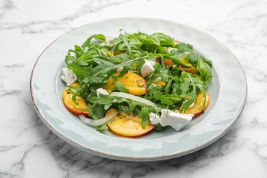 Photo of Tasty salad with arugula, cheese, peach and basil on white marble table, closeup