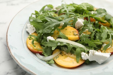 Photo of Tasty salad with arugula, cheese, peach and basil on white marble table, closeup