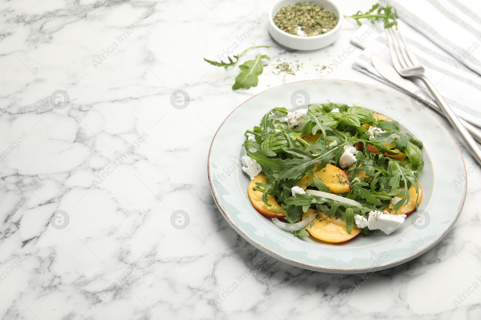 Tasty salad with arugula, cheese, peach, basil and spices on white marble table, closeup. Space for text Photo of Tasty salad with arugula, cheese, peach, basil and spices on white marble table, closeup. Space for text