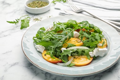 Photo of Tasty salad with arugula, cheese, peach, basil and spices on white marble table, closeup