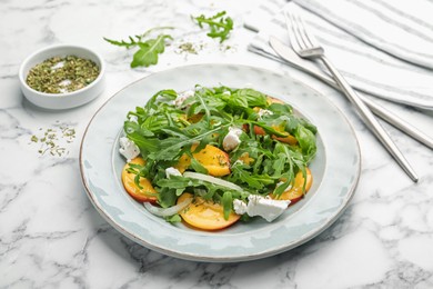 Photo of Tasty salad with arugula, cheese, peach, basil and spices on white marble table, closeup