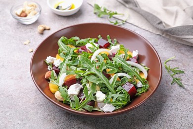 Photo of Tasty salad with arugula, cheese, peach, beetroot and nuts on grey table, closeup