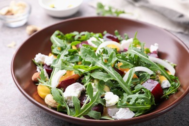 Photo of Tasty salad with arugula, cheese, peach, beetroot and nuts on grey table, closeup