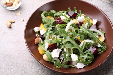 Photo of Tasty salad with arugula, cheese, peach, beetroot and nuts on grey table, above view