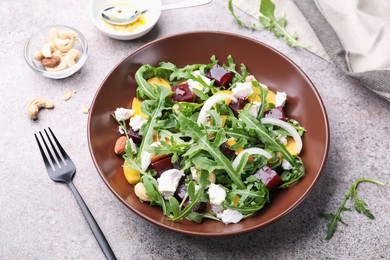 Photo of Tasty salad with arugula, cheese, peach, beetroot and nuts on grey table, above view