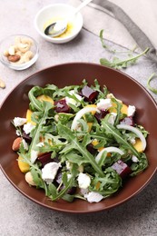 Photo of Tasty salad with arugula, cheese, peach, beetroot and nuts on grey table, above view