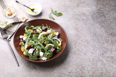 Photo of Tasty salad with arugula, cheese, peach, beetroot and nuts on grey table, above view. Space for text
