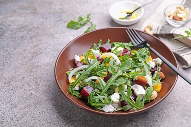 Photo of Tasty salad with arugula, cheese, peach, beetroot and nuts on grey table, closeup. Space for text