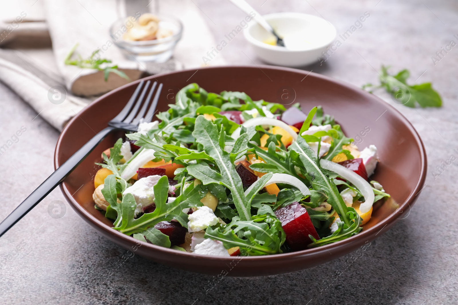 Tasty salad with arugula, cheese, peach, beetroot and nuts on grey table, closeup Photo of Tasty salad with arugula, cheese, peach, beetroot and nuts on grey table, closeup