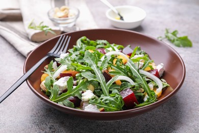 Photo of Tasty salad with arugula, cheese, peach, beetroot and nuts on grey table, closeup