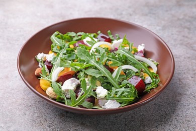 Photo of Tasty salad with arugula, cheese, peach, beetroot and nuts on grey table, closeup