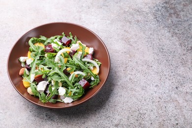 Photo of Tasty salad with arugula, cheese, peach, beetroot and nuts on grey table, above view. Space for text