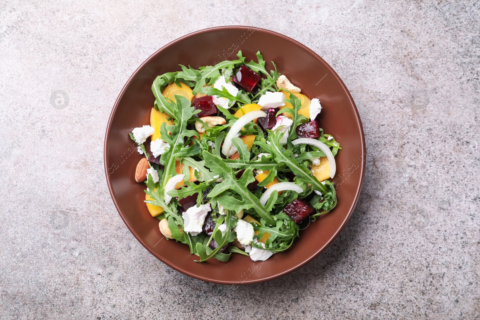 Tasty salad with arugula, cheese, peach, beetroot and nuts on grey table, top view Photo of Tasty salad with arugula, cheese, peach, beetroot and nuts on grey table, top view