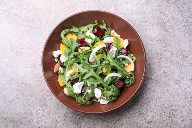 Photo of Tasty salad with arugula, cheese, peach, beetroot and nuts on grey table, top view