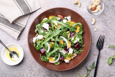Photo of Tasty salad with arugula, cheese, peach, beetroot and nuts on grey table, flat lay